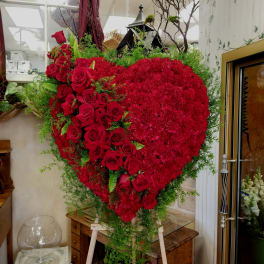 Heart-shaped red rose and carnation arrangement on an easel