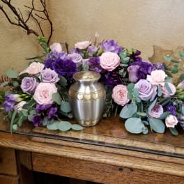 Lavender and pink roses arranged around a silver urn