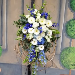 Tall floral spray with white and blue flowers in a twig frame