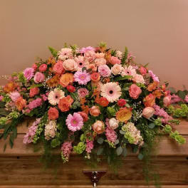 Large pink and peach floral casket spray with roses and daisies
