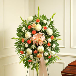 Standing floral wreath with white and coral flowers and a peach ribbon
