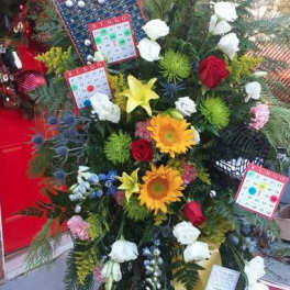 Tall standing floral display with sunflowers, roses, and bingo cards