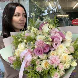 Woman holding a large bouquet of pink and cream flowers with a ribbon