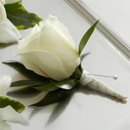 White rose boutonniere with green leaves and a pearl pin