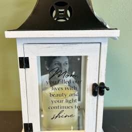 White wooden memorial lantern with a candle and tribute message