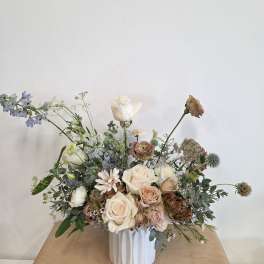 Loose bouquet of cream and blush roses in a white vase