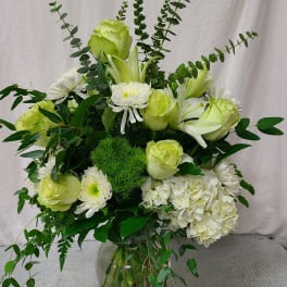 White and pale green floral arrangement in a glass vase