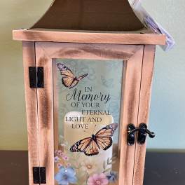 Wooden memorial lantern with butterfly artwork and a candle inside