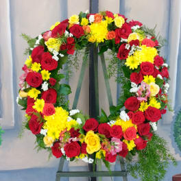 Large floral wreath of red, yellow, and pink roses on an easel