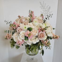 Large blush and white rose arrangement in a glass pedestal vase