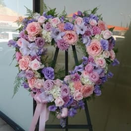 Heart-shaped floral wreath with pink and lavender roses on an easel