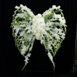 Large white floral spray arranged in a winged shape on a stand