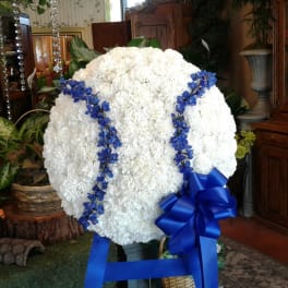 Large white floral standing spray with blue ribbon and blue accents