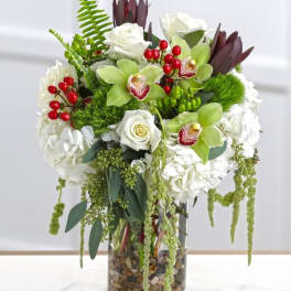 White roses and green orchids in a glass vase with red berries