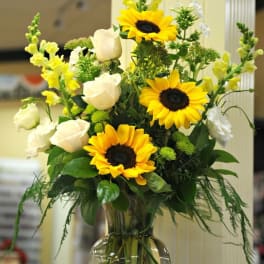 Sunflower and white rose arrangement in a clear glass vase