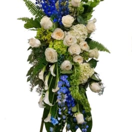 Tall standing floral spray with white roses, blue delphinium, and green accents