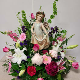 Floral arrangement with a figurine centerpiece and pink, white, and purple flowers