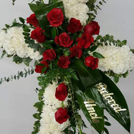 Cross-shaped floral spray with red roses and white blooms on an easel