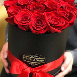 Red roses arranged in a black hatbox with a red ribbon