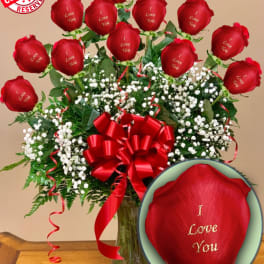 Red roses with "I Love You" text in a glass vase with baby's breath and a red bow