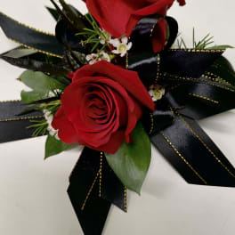 Two red roses with black ribbon accents and small white filler flowers