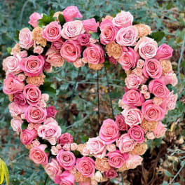 Heart-shaped arrangement of pink roses and spray roses