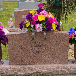 Colorful floral cemetery arrangement around a gravestone