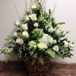 White roses and hydrangeas in a wicker basket arrangement