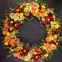 Heart-shaped floral wreath with orange, yellow, and burgundy blooms