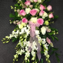 Pink and white floral spray with ribbon on a dark background