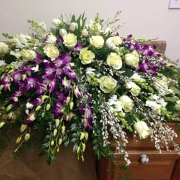 Large white and purple floral spray arranged over a casket