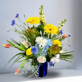 Mixed bouquet in a blue vase with yellow, white, and blue flowers