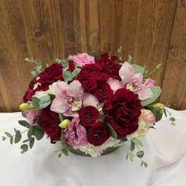 Bouquet of red roses and pink orchids in a low vase