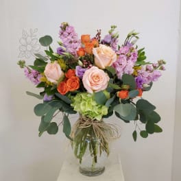 Mixed bouquet of roses and purple flowers in a glass vase