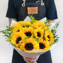 Bouquet of bright yellow sunflowers wrapped in white paper
