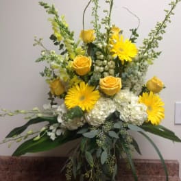 Yellow roses and gerbera daisies in a vase with white hydrangeas