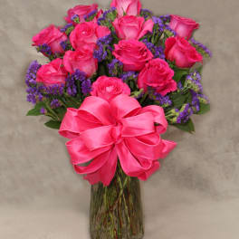 Pink roses in a glass vase with a large pink bow