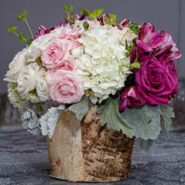 Pink and white floral arrangement in a birch bark container