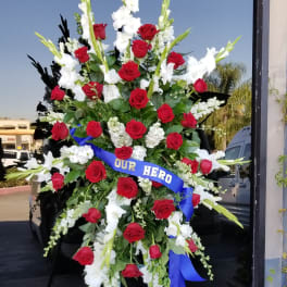 Large standing spray of red roses and white gladiolus with a blue ribbon