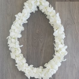White floral lei arranged in an oval shape on a wood floor