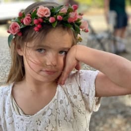 Girl wearing a pink floral crown with small roses and berries