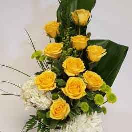 Yellow roses and white hydrangeas in a square vase