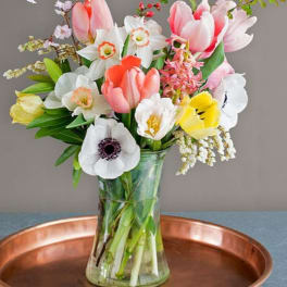 Mixed bouquet of tulips and daffodils in a glass vase