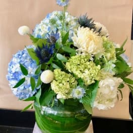 Blue and white floral arrangement in a green glass vase
