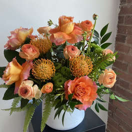 Orange and peach floral arrangement in a white vase