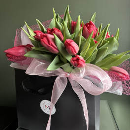 Pink tulips arranged in a black gift box with a pink ribbon