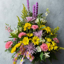 Mixed bouquet of yellow, pink, and lavender flowers in a metal bucket