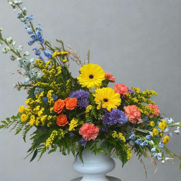 Colorful mixed flower arrangement in a white pedestal vase
