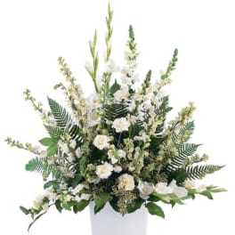 White floral arrangement in a square white vase with tall greenery
