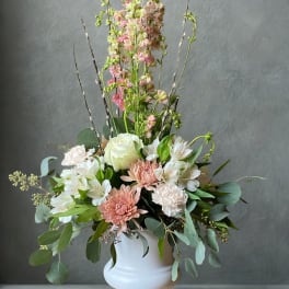 Pastel floral arrangement in a white pedestal vase with tall pink blooms